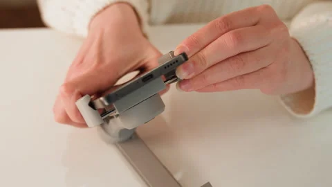 Hands measuring metal hinge with caliper on white tabletop, showing precise Stock Footage 343530532
