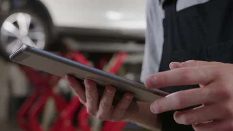 Hands of a mechanic with a digital tablet at a car service station Stock Footage 253173720