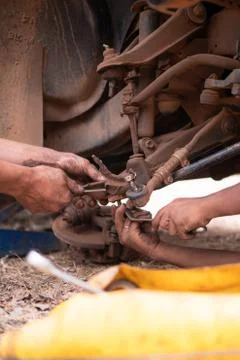 Hands of mechanic fixing wishbone control arm of the truck part to repair fro Stock Photos