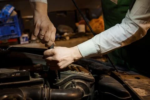 Hands of a mechanic working on a car engine with tools in a garage setting 스톡 사진