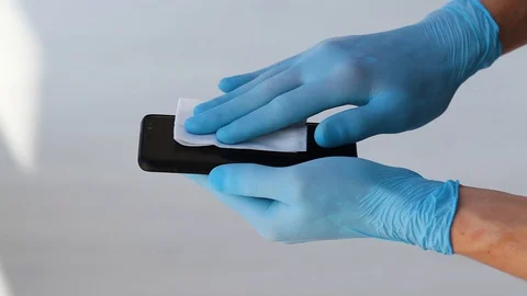 Hands in medical blue rubber gloves to rub a mobile phone screen with a napkin. Stock Footage 128986187