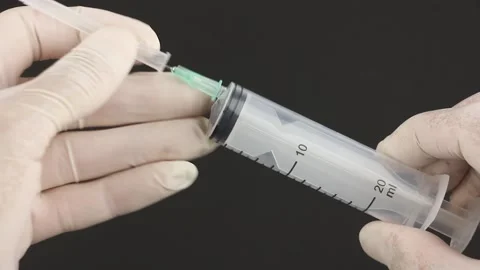 Hands in medical gloves take disposable syringe, remove cap from needle 動画素材 160053589