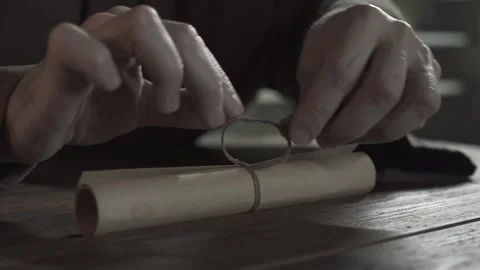 Hands of a medieval monk tying a simple knot with a string on a scroll Stock Footage 337930128