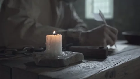 Hands of medieval prisoner in rusty shackles warming over a burning candle Stock Footage 340322649