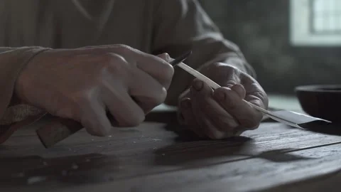 Hands of a medieval prisoner sharpening a goose quill inside a dark dungeon 스톡 동영상 340502620