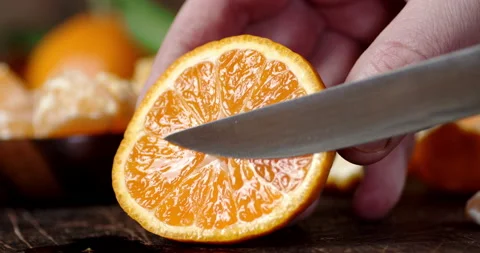 Hands men with a knife squeeze the juice of ripe Mandarin. Stock Footage 130513595