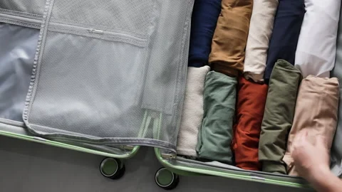 Hands methodically place folded clothing in perfect alignment inside travel case Video stock 311975365