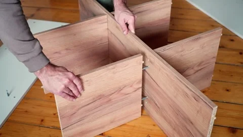 Hands meticulously assembling stylish wooden furniture pieces in a contemporary Stock Footage 302655475