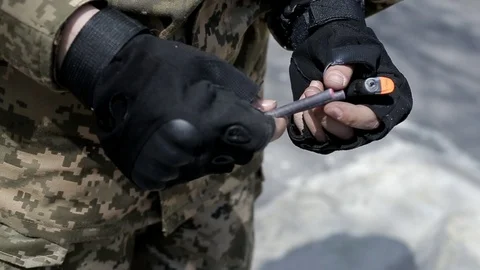 The hands of a military instructor set fire to a smoke bomb Stock Footage 89434897