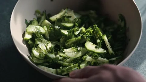 Hands mix chopped vegetables in a large bowl while preparing a salad. Stockbeeldmateriaal 338304141