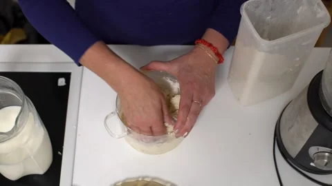 Hands mix dough for baking on a kitchen counter with tools and ingredients Stock Footage 330649861