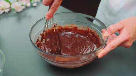 Hands mixing chocolate batter with whisk in indoor kitchen Vidéo 342884932