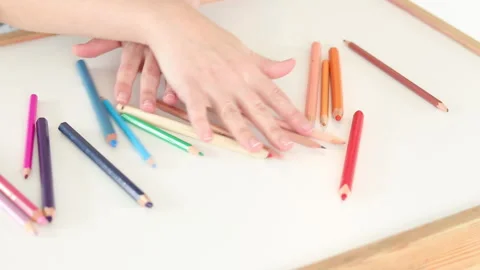 Hands mixing colored pencils on white table from gradient to random arrangement Stock Footage 331719367