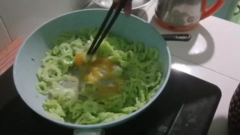 Hands Mixing Eggs with Bitter Melon Before Cooking Stock Footage 337924249