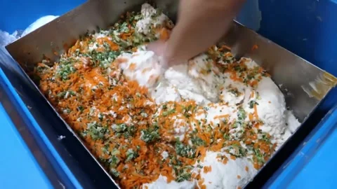 Hands mixing fresh dough with shredded carrots and green onions for Korean fish Stock Footage 337372781