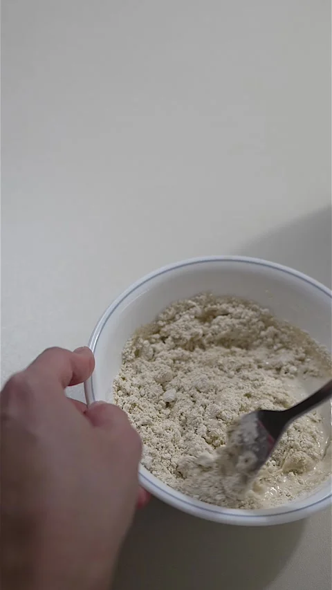 Hands mixing pancake batter with fork in white bowl Stock-Footage 333154116