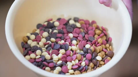 Hands mixing ruby white and dark chocolate callets in bowl confectionary concept Video stock 239382940