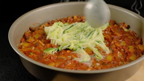 Hands Mixing Zucchini into Vegetable Stew in Bowl Cooking Stock Footage 341441267