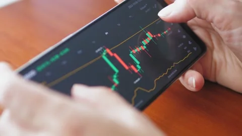 Hands with a mobile phone, checking stock market data. Scrolling through Stock Footage 218425149