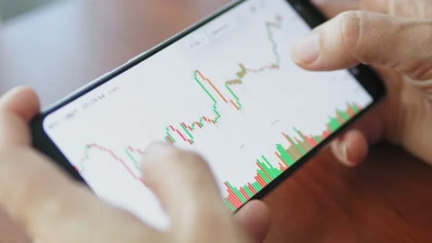 Hands with a mobile phone, checking stock market data. Scrolling through Stock Footage 218624411