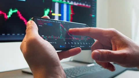 Hands with a mobile phone, checking stock market data. Stock Footage 233106034