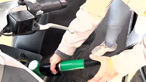 The hands of a motorcyclist insert a gas valve into the gas tank for refueling Stock Footage 254969487