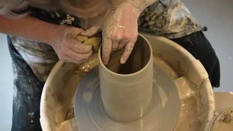 Hands mould pot rotating on potter's wheel and moisten with its sponge Stock Footage 240946975