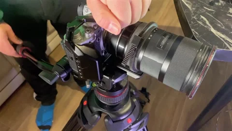 Hands mounting tripod plate on video camera close-up, securing quick release Stock Footage 333649571