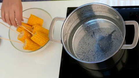 Hands move corn on a stick of pan Stock-Footage 84300221