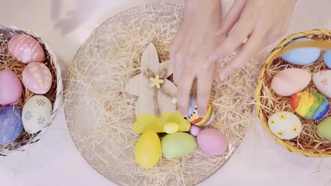 Hands moving colorful Easter eggs into basket on festive background. Stock Footage 236341507