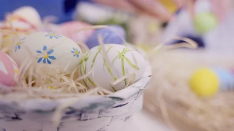Hands moving painted Easter eggs into basket on festive background. Stock-Footage 236341558
