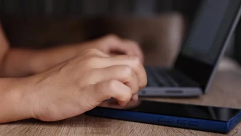 Hands multitasking between laptop and smartphone, close-up, multitasking Stock Footage 328243418