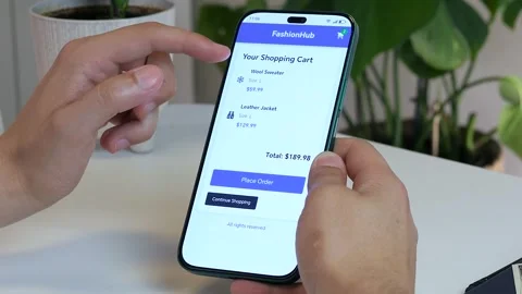 Hands navigate an e-commerce app to review saved items in the shopping cart Stock Footage 316220089