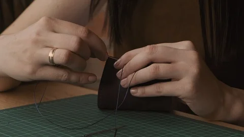 Hands with needle and strings making wallet in workshop. Handmade leather goods. Video stock 116434323