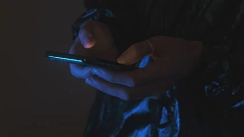 Hands in neon dark lighting using a mobile phone to scroll and typing Stock Footage 160125497