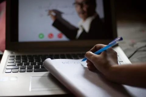 Hands on notebook while attending online classes at laptop in home isolation  Stock Photos