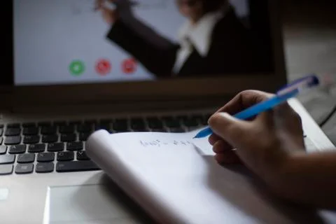 Hands on notebook while attending online classes at laptop in home isolation  Stock Photos