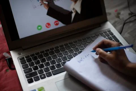 Hands on notebook while attending online classes at laptop in home isolation  Stock Photos