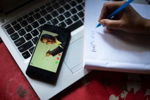 Hands on notebook while attending online classes at cellphone in home isolati Stock Photos