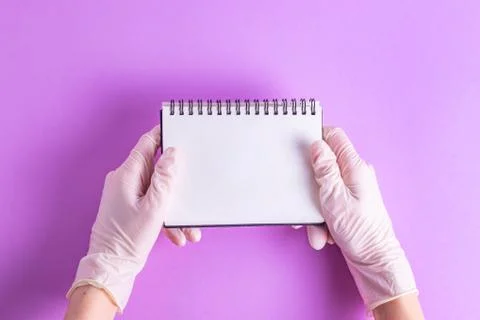 Hands with notepad for notes in rubber gloves on a purple background Stock Photos