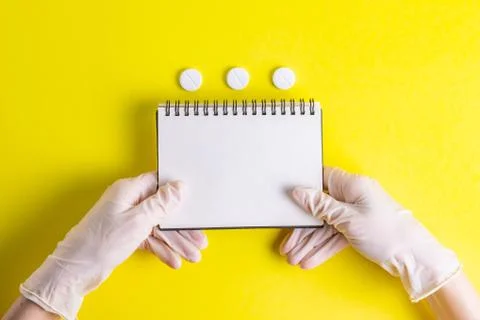 Hands with a notepad in rubber gloves with a thermometer on a yellow background Stock Photos