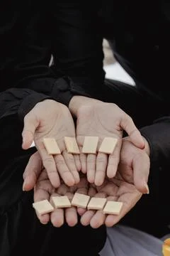 Hands offering small rectangular beige tiles in a gesture of sharing Stock Photos