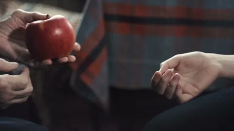 Hands of an old man pass an apple into the hands of a teenager Stock Footage 102335876