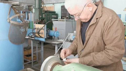 Hands old master grind detail on bench grinder, rough grinding machine, close Vidéo 105840014