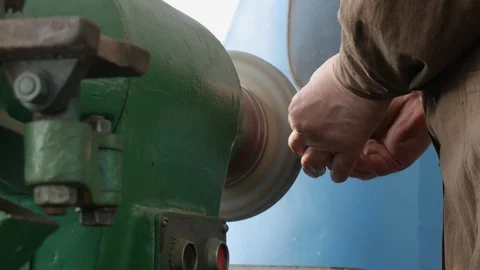 Hands old master grind detail on bench grinder, rough grinding machine, close Vidéo 105840158