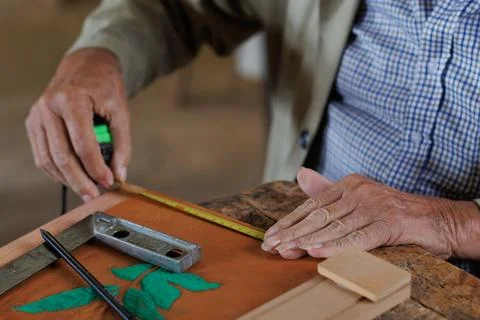 Hands of an older man, working on embossed leather, and taking notes. Stock Photos