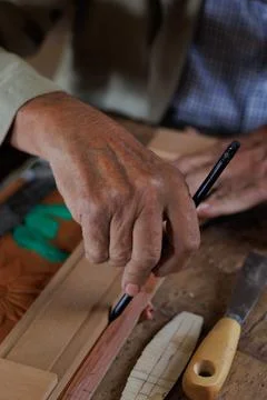 Hands of an older man, working on embossed leather, and taking notes. Stock Photos