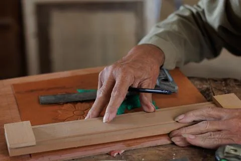 Hands of an older man, working on embossed leather, and taking notes. Stock Photos