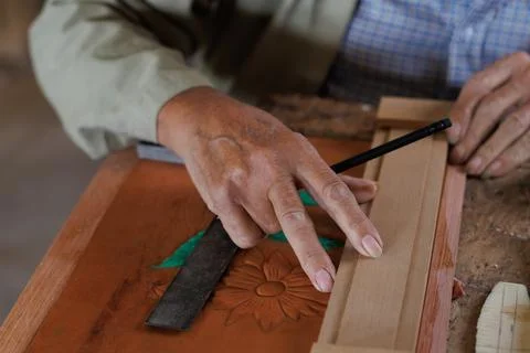 Hands of an older man, working on embossed leather, and taking notes. Stock Photos