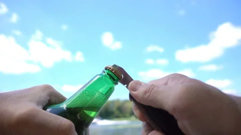 Hands open beer bottle in slow motion on nature Vídeo Stock 134833639